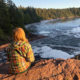 ein Mädchen sitzt auf einem Felsen am Meer